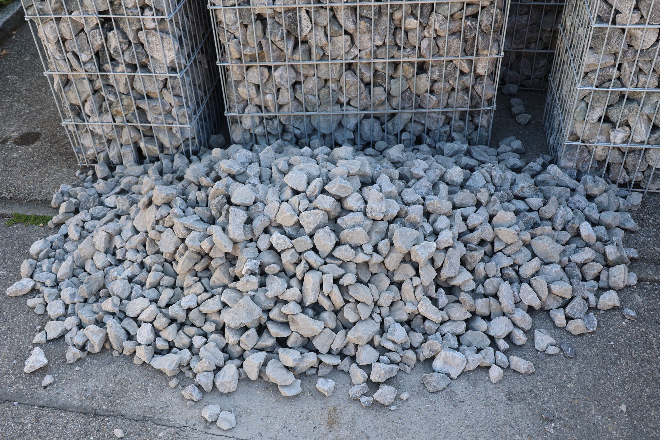 A pile of rocks is sitting on the ground. The rocks are grey and appear to be large. .